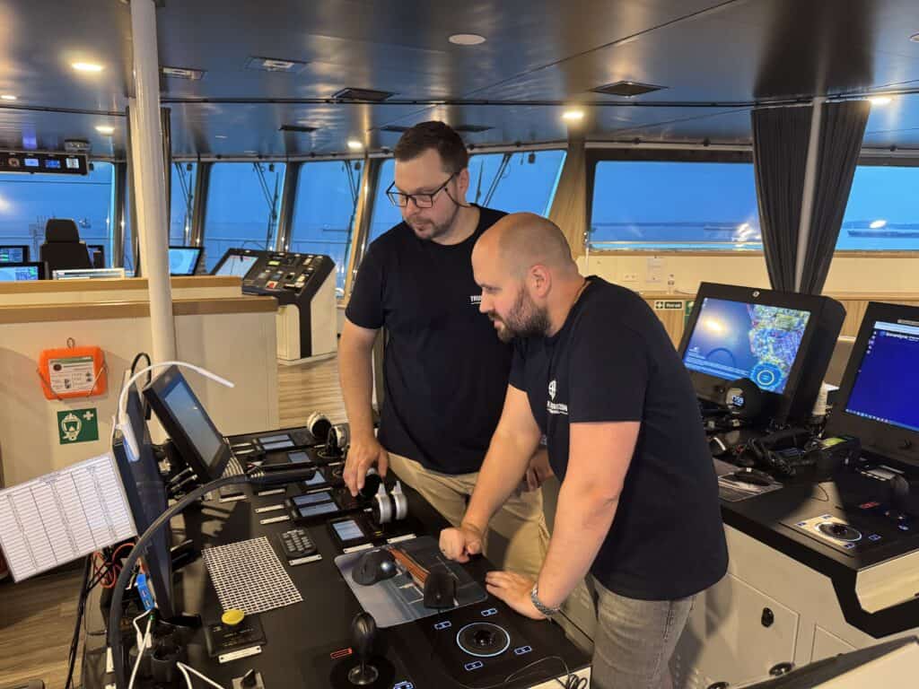 Two men navigating ship bridge controls