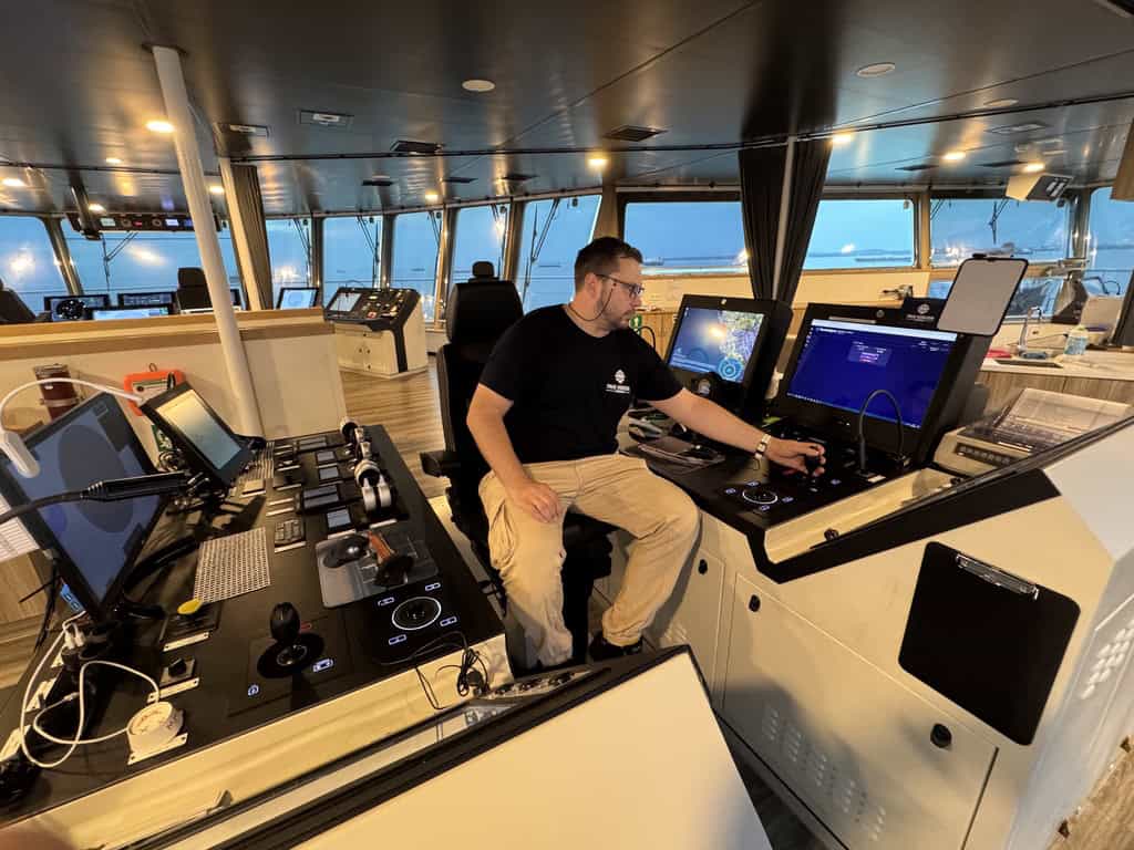 Person operating ship's control panel on bridge.